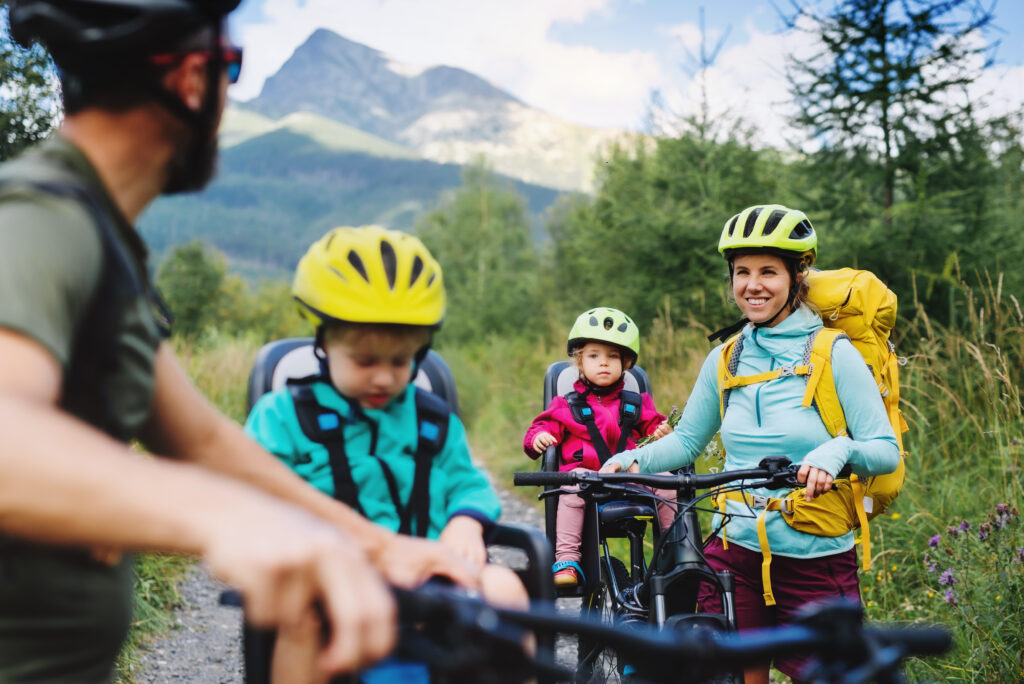 A family with young children cycling outdoors in the summer countryside, Tatra Mountains, Slovakia.
